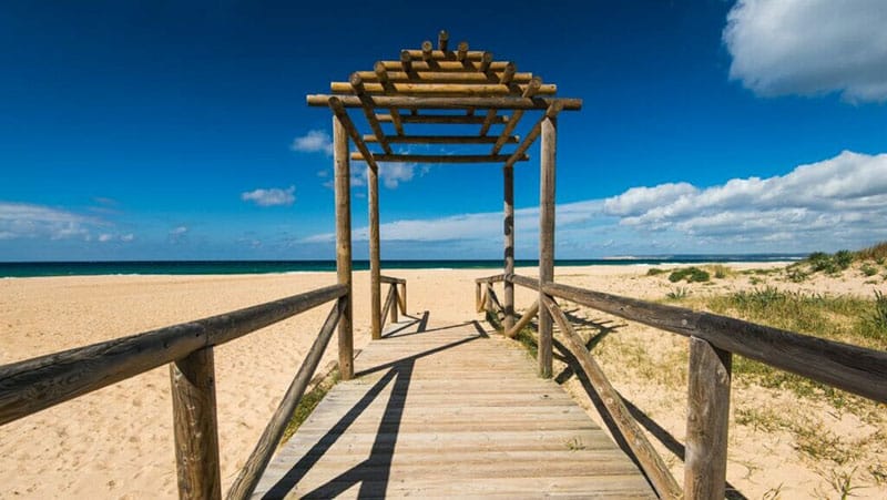 Wide sandy beach of Zahara de los Atunes with calm Atlantic waves and natural dunes.
